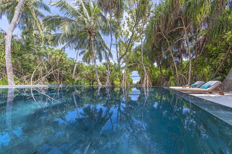 View of beach and ocean from across swimming pool of villa