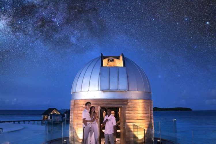 Guest and our Stars Guru standing in front of the over water observatory at night