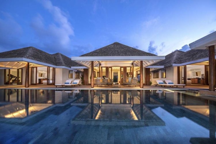 Exterior view over swimming pool and outdoor terrace at Two Bedroom Beach Pool Residence at dusk
