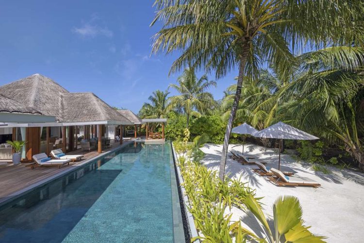 Exterior view of swimming pool, outdoor terrace and beach with sun-loungers at Two Bedroom Beach Poo