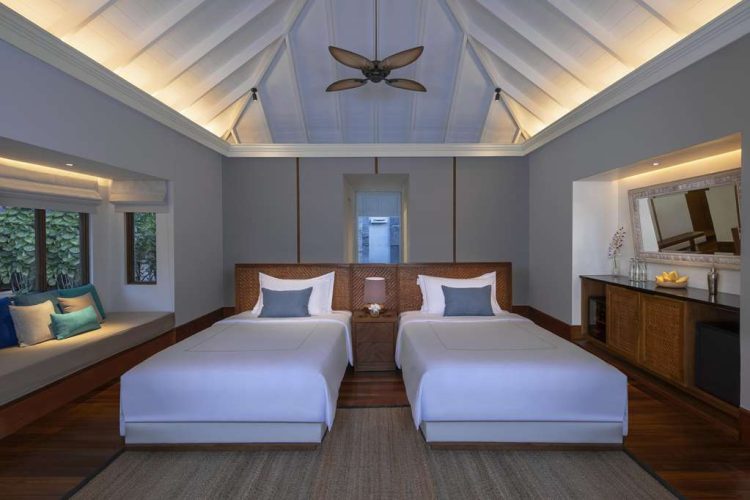 Interior view of twin bedroom in Beach Pool Residence with seating area and mini-bar cabinet