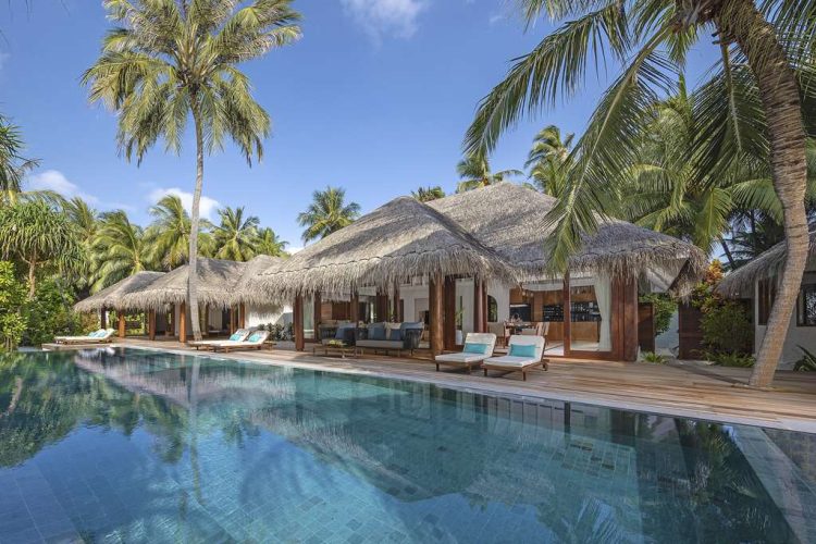 Exterior view of Three Bedroom Beach Pool Residence across swimming pool with sun-loungers on outdoo