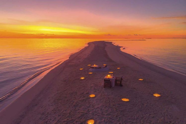 Aerial view of Dining By Design beach dinner setup at sunset